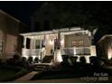 Evening view of the home's front elevation with a lighted porch and landscaped yard at 7732 Waverly Walk Ave, Charlotte, NC 28277
