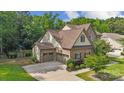 Aerial view of the home with three-car garage, nice lawn, and mature tree coverage at 11412 Preservation Ln, Charlotte, NC 28278