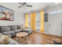 Comfortable living room featuring hardwood floors, large sofa, and bright yellow curtains at 12342 Carrigan Ct, Huntersville, NC 28078
