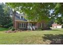 Traditional brick home with a well-maintained lawn and inviting front porch framed by mature trees at 14232 Kendalton Meadow Dr, Mint Hill, NC 28227