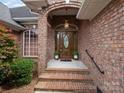 Elegant brick entryway with a classic wooden front door and decorative plants at 2872 Wheat Field Ct, Lincolnton, NC 28092