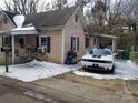 View of the home's front exterior, showcasing a covered porch and driveway with a car, all lightly dusted with snow at 2942 Reid Ave, Charlotte, NC 28208