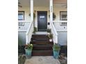 Close-up of front porch featuring a black front door and decorative plants on the wooden stairs at 323 Keswick Ave, Charlotte, NC 28206