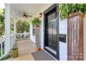 Inviting front porch with a ceiling fan, black front door, and decorative greenery at 323 Keswick Ave, Charlotte, NC 28206