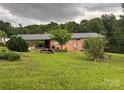 The backyard features a brick home with a covered area, complemented by lush landscaping and mature trees at 356 Lucky Hollow Rd, Hickory, NC 28601
