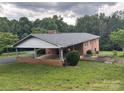 Brick home with an attached carport and large grassy yard, nestled amongst mature trees for a private feel at 356 Lucky Hollow Rd, Hickory, NC 28601