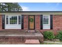 Charming brick home entrance with a decorative wreath, welcome mat, and window shutters at 522 Ne Connector Hwy, Albemarle, NC 28001