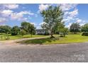 Large grassy lot with mature trees surrounding a light blue home with a white porch at 7785 Crestwood Dr, Kannapolis, NC 28081
