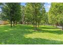 Expansive green backyard with mature trees and a view of the home in the distance at 8101 Truelight Church Rd, Mint Hill, NC 28227
