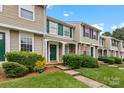 Neat townhome row displaying manicured lawns, lush shrubbery, and uniform green door accents at 9606 Vinca Cir # E, Charlotte, NC 28213