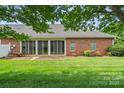 Back of the brick house featuring a screened in porch and green yard at 104 Mooreland Ne Dr, Conover, NC 28613