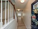 Welcoming entryway showcasing hardwood floors, a staircase with white railings, and a decorated front door at 12131 Honor Guard Ave, Charlotte, NC 28277