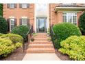 Charming brick staircase leading to front door with decorative glass, complemented by manicured bushes and flower accents at 2019 Heirloom Ct, Matthews, NC 28104