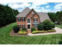 Beautiful two-story brick home with manicured lawn, mature trees, and a welcoming front entrance at 2019 Heirloom Ct, Matthews, NC 28104