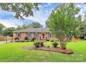 A well-manicured front lawn leads to a charming brick house with a red front door and blue shutters at 3304 Chilham Pl, Charlotte, NC 28226