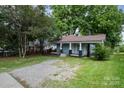 Cozy single-story home featuring a classic front porch and a gravel driveway at 4510 Wildwood Ave, Charlotte, NC 28208
