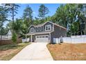 View of the property showcasing its gray siding, manicured lawn, long driveway, and a two-car garage at 6425 Pamela St, Huntersville, NC 28078