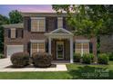 Inviting brick home exterior featuring a covered porch, black shutters, and landscaped shrubs at 704 Millstream Dr, Rock Hill, SC 29732