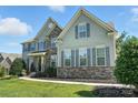 Charming home featuring gray siding, stone accents, manicured lawn, and gray shutters at 8427 Penton Pl, Harrisburg, NC 28075