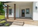 Covered front porch with wooden pillars, brick steps, and decorative landscaping at 1010 Oneil Dr, Monroe, NC 28112
