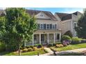 Attractive two-story home with a covered front porch and lush landscaping around the yard at 11806 Stirling Field Dr, Pineville, NC 28134