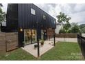 Modern home with fenced backyard, concrete patio, outdoor lighting, and black exterior at 2107 W Trade St, Charlotte, NC 28216