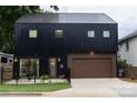 Contemporary two-story black home with a metal roof, brown garage door, and manicured front yard at 2107 W Trade St, Charlotte, NC 28216