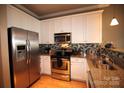Kitchen featuring stainless steel appliances, granite countertops, tile backsplash, and hardwood floors at 230 S Tryon St # 304, Charlotte, NC 28202