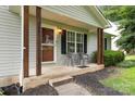 Close up of the inviting front porch with seating, dark pillars and well-kept garden at 704 Willow Rd, Salisbury, NC 28147