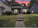 Charming home featuring manicured lawn and welcoming front porch with inviting chairs and decor at 1228 Rising Oak Dr, Charlotte, NC 28206