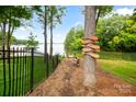Scenic backyard with a black fence, water view, and a tree decorated with wooden paddles at 16112 Terry Ln, Huntersville, NC 28078