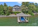 Lake home featuring a boat dock and boat with water views and well maintained landscaping at 18007 Harbor Light Blvd, Cornelius, NC 28031