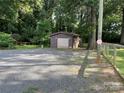 Detached garage features a fresh coat of paint, ample parking, and mature shade trees at 2411 Rebecca Ave, Charlotte, NC 28208
