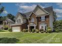 Charming two-story brick home boasts lush landscaping and an attached two-car garage at 4966 Riverview Dr, Harrisburg, NC 28075