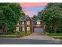 Charming two-story brick home with green shutters, attached garage, and manicured lawn at sunset at 6016 Graburns Ford Dr, Charlotte, NC 28269