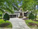 Attractive home featuring a stone facade, well-maintained landscaping, and a driveway leading to a three-car garage at 8016 Pemswood St, Charlotte, NC 28277