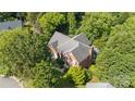 An aerial view of a two-story brick home nestled amongst lush, mature trees at 8900 Cumbria Ct, Huntersville, NC 28078