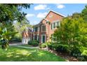 A full view of a two story brick home with manicured landscaping and an attached two car garage at 8900 Cumbria Ct, Huntersville, NC 28078