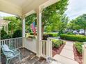 Inviting front porch with a chair, American flag, and view of the lush, landscaped front yard at 9730 White Frost Rd, Charlotte, NC 28277