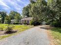 Quaint home featuring a spacious yard with gravel driveway and additional storage shed at 310 E Houston St, Monroe, NC 28112