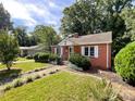 Charming brick home featuring a well-manicured front yard, walkway, and manicured landscape at 310 E Houston St, Monroe, NC 28112