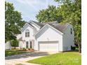Well-maintained two-story home with white siding, attached garage, and a lush green lawn surrounded by mature trees at 411 Carlisle Dr, Indian Trail, NC 28079