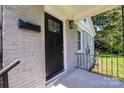 Close-up of the black front door with glass panels and a brick-covered porch at 4413 Tillman Rd, Charlotte, NC 28208