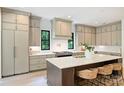 Bright kitchen featuring a center island with bar stools, custom cabinets, and modern appliances at 7011 Chateau Bordeaux Ln, Charlotte, NC 28270