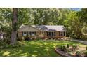 Charming brick ranch home with lush landscaping, mature trees, and a welcoming yellow front door at 11329 Torino Rd, Matthews, NC 28105