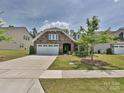 Inviting home with a manicured lawn, stone facade, and two-car garage on a sunny day at 15614 Aviary Orchard Way, Charlotte, NC 28278