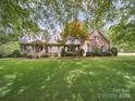 Inviting brick home with lush green lawn, mature landscaping, and a charming front porch at 394 E Goldmine Rd, Wadesboro, NC 28170