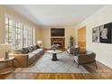Cozy living room features a brick fireplace, hardwood floors, and large windows at 6921 Thermal Rd, Charlotte, NC 28211