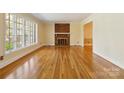 Bright living room featuring gleaming hardwood floors, large windows, and a cozy brick fireplace with white mantel at 6921 Thermal Rd, Charlotte, NC 28211