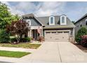 Charming home featuring a two-car garage and a manicured lawn with mature tree and American flag at 741 Garrett Green Way # 64, Fort Mill, SC 29715